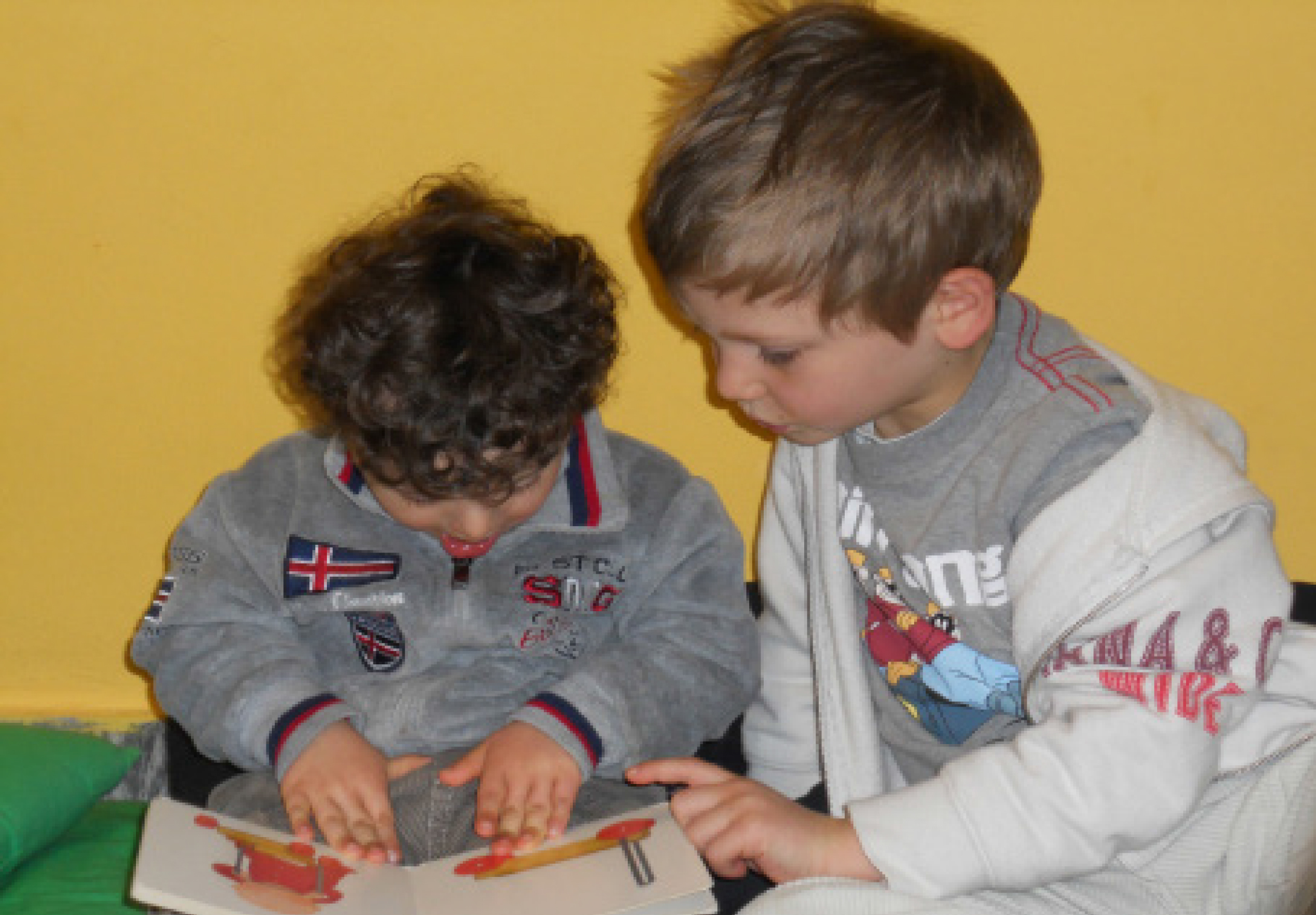 insieme due bambini di età diversa che guardano insieme un libro